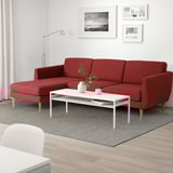 Sofá modular SMEDSTORP rojo, de estilo retro moderno, con espuma de alta resiliencia. Mesa de centro blanca, alfombra gris, fotos en blanco y negro.