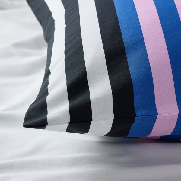 Funda de almohada a rayas con rayas vibrantes y alternas en una suave mezcla de algodón, perfectamente doblada sobre una superficie blanca.