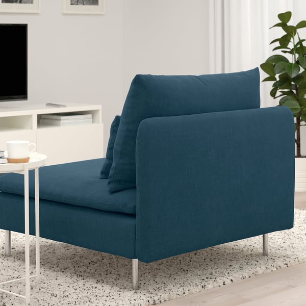 Sofá seccional SÖDERHAMN azul oscuro con asientos profundos, patas altas y cojines sueltos en un acogedor salón con mesa de centro y plantas.