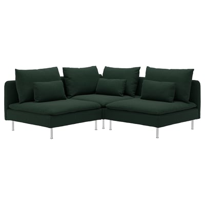 Sofá modular esquinero moderno de color verde oscuro con numerosas almohadas, elevado sobre delgadas patas cromadas.