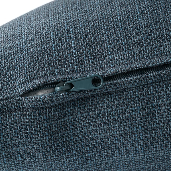 Primer plano de un sofá moderno y profundo con una elegante cremallera plateada sobre una tela tejida texturizada.