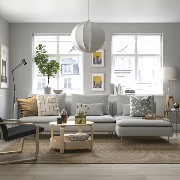 Conjunto de sofás SÖDERHAMN grises, profundos, con grandes cojines y mesa redonda de madera junto a un gran ventanal con vistas a la ciudad.