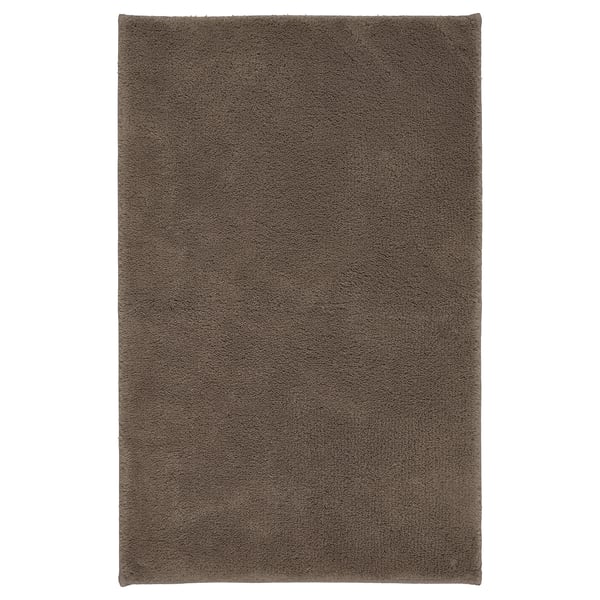 Una alfombra de baño SÖDERSJÖN marrón, de forma rectangular, con una superficie suave de algodón y respaldo de látex.