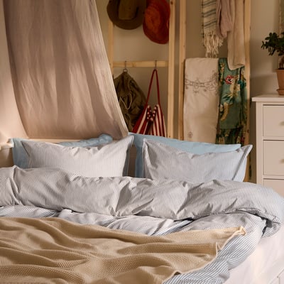 Una cama acogedora con un juego de fundas nórdicas SOLFIBBLA a rayas azules y blancas, bandera americana y un ambiente acogedor.