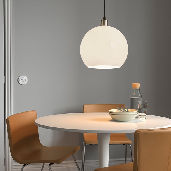 Comedor minimalista con sillas naranjas, mesa blanca y lámpara colgante.