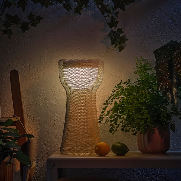 Una lámpara decorativa en una estantería con frutas y plantas, que emite un cálido resplandor.