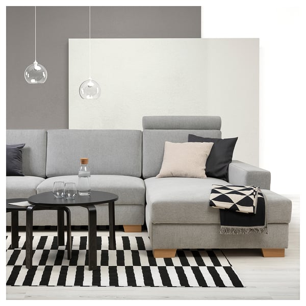 Sala de estar moderna con sofá SÖRVALLEN gris, alfombra de rayas blancas y negras, mesa de centro negra, lámparas colgantes y accesorios en el sofá.