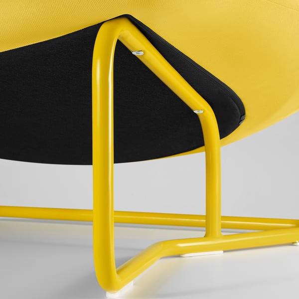 Primer plano de una silla moderna con estructura de metal amarillo y asiento negro, que muestra un diseño elegante y una artesanía robusta.