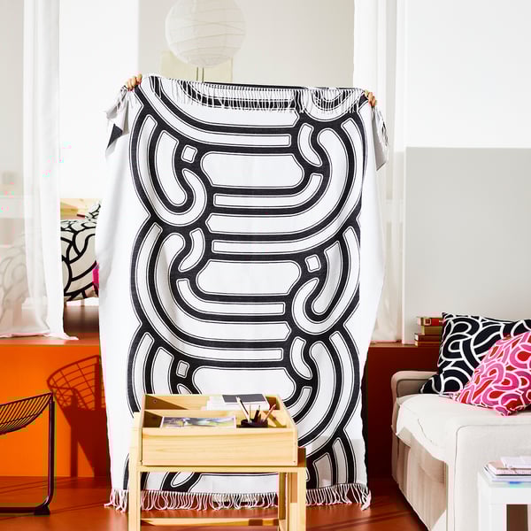 Gran manta estampada en blanco y negro, ideal para la siesta y la decoración del hogar, expuesta en una luminosa sala de estar.