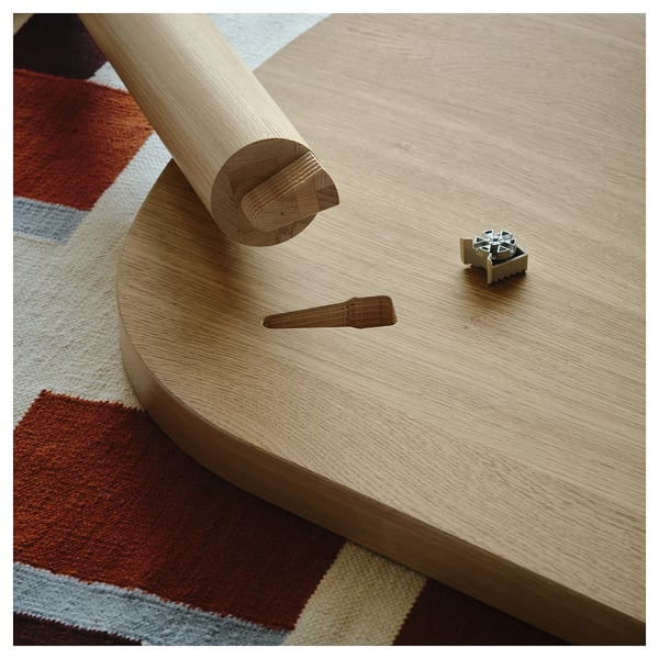 Parte de mesa de madera clara con un accesorio metálico y una clavija. Se muestra un montaje simple y eficiente, adecuado para uso en interiores.