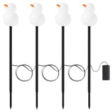 Cuatro luces led blancas con forma de muñeco de nieve sobre palos negros, con narices naranjas, alimentadas por una caja de baterías, perfectas para la decoración navideña al aire libre.