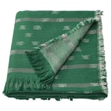 Una manta de algodón verde oscuro, adornada con motivos y flecos en blanco roto y gris en sus bordes.