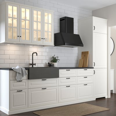 Cocina moderna blanca con fregadero de cuarzo gris oscuro. Gabinetes con frente de vidrio, campana negra y grifo de acero inoxidable. Fíjate en el exclusivo armario alto.