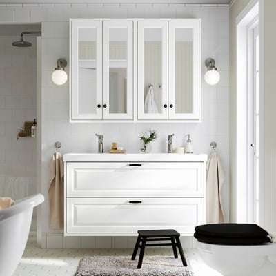 Moderno baño blanco con tocador TÄNNFORSEN, espejo grande y taburete negro.