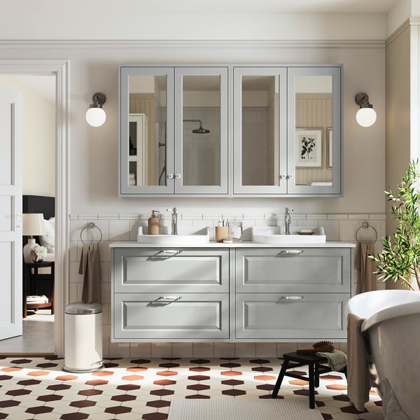 Tocador de baño gris moderno, espejos grandes, manijas elegantes, encimera blanca, cajones espaciosos.