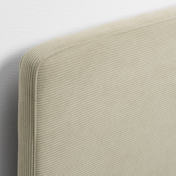 Detalle de cabecero tapizado en color beige; Tejido suave y texturizado con meticulosas costuras, parte de una estructura de cama moderna.