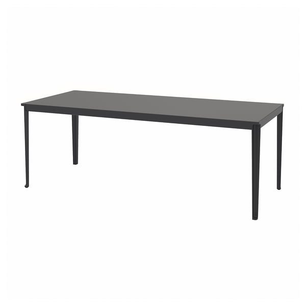 Una mesa de comedor de exterior TEGELÖN en color negro, de forma rectangular con patas metálicas y tablero de composite.