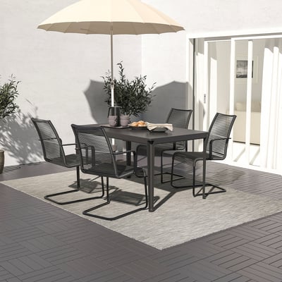 Conjunto de patio moderno con mesa, 4 sillas y sombrilla sobre alfombra gris. La mesa tiene jarrón y artículos, con puertas abiertas detrás.