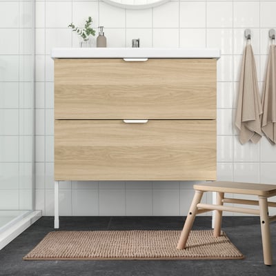 Baño minimalista con mueble de madera, lavabo, ducha de cristal y colchoneta TOFTBO.