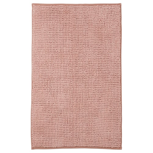 Una alfombra de baño TOFTBO en color beige. Es rectangular, afelpada y está hecha de poliéster reciclado.