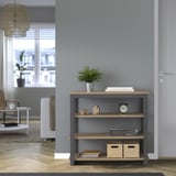 Consola TRÄKUMLA con libros, planta, reloj. Gris con estantes de madera, contra la pared.
