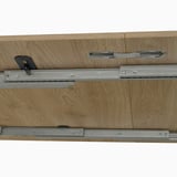 El mecanismo de mesa transformable, que destaca los rieles metálicos que permiten que la mesa se extienda o se pliegue, útil para comer en un espacio eficiente.