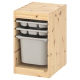Un mueble de almacenamiento de madera IKEA TROFAST en pino claro, con tres bandejas de almacenamiento de plástico con compartimentos y un gran contenedor de plástico.