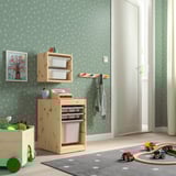 Sala de juegos para niños con almacenamiento TROFAST, juguetes en alfombra, camisa en percha, arte de pared en el árbol.