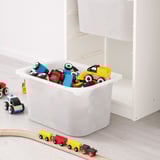 Contenedor de almacenamiento blanco TROFAST lleno de coloridos coches de madera, fácil de acceder para los niños y organizar los juguetes.