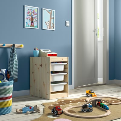 Sala de juegos para niños con almacenamiento TROFAST, juguetes y paredes azules.