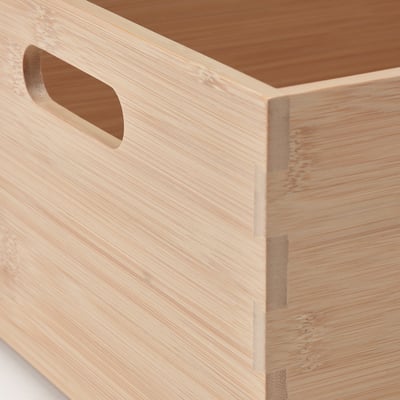 Una caja de almacenamiento rectangular de bambú con dos asas, adecuada para organizar utensilios de cocina o artículos pequeños, en color madera natural.