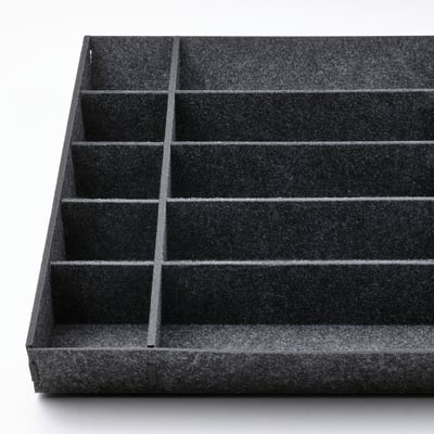 Un organizador de cajones UPPDATERA negro con múltiples compartimentos para guardar utensilios de cocina.