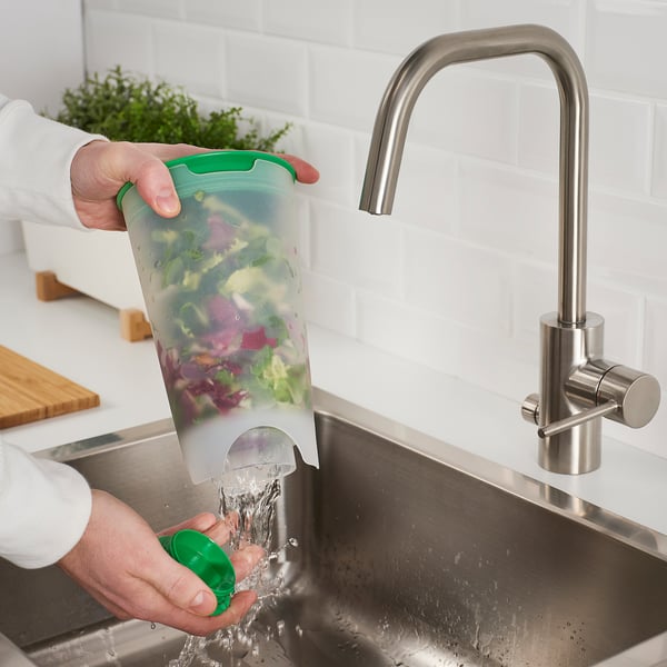 La persona enjuaga la ensalada en una coctelera UPPFYLLD con un colador debajo de un grifo.