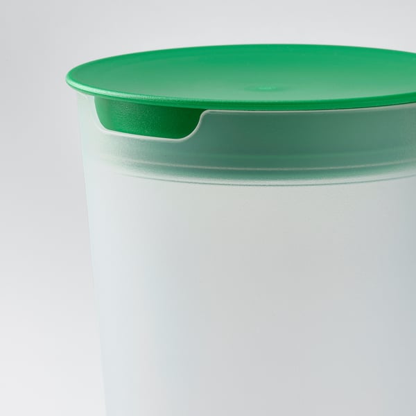 Tapa de ensaladera verde con asa empotrada en recipiente blanco.