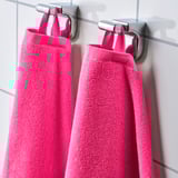 Dos toallas de color rosa brillante cuelgan cuidadosamente de ganchos metálicos, mostrando su tela absorbente y de secado rápido y su color vibrante.