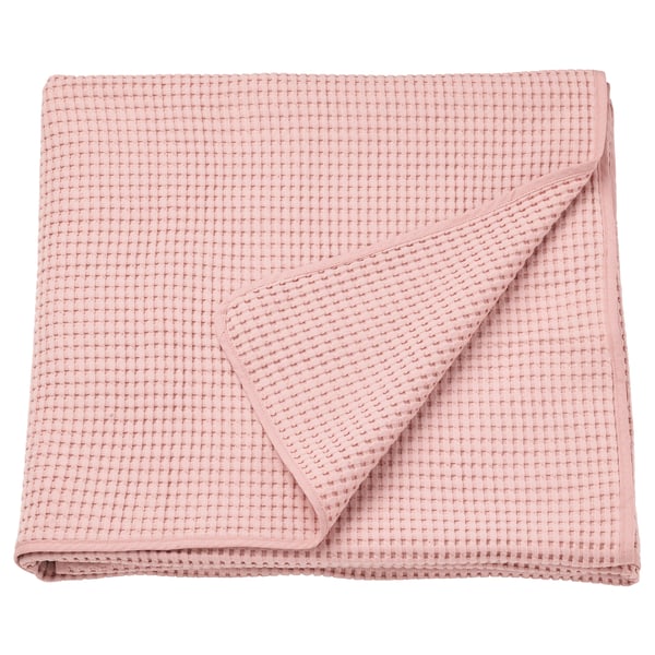 Una colcha VÅRELD cuidadosamente doblada en rosa claro, confeccionada en 100% algodón con un diseño de gofre texturizado.