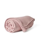 Una colcha de algodón VÅRELD rosa enrollada, con un diseño de tejido texturizado, adecuada para la calidez y la decoración.