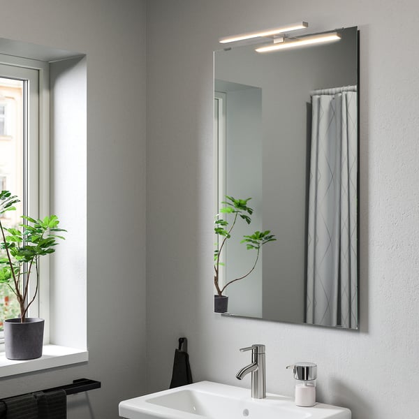 Baño moderno con lámpara de pared VÅTHULT, diseño elegante, encima del lavabo.