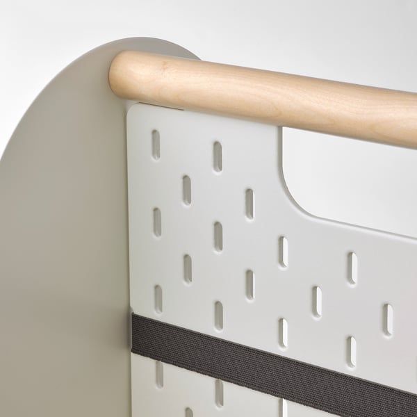 Primer plano del organizador VATTENKAR: mango de madera, tablero de clavijas blanco con ranuras, correa elástica, montado en pared gris.