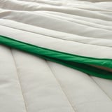 Elegante colcha de tela reciclada en color blanco con ribetes en verde oscuro que luce una textura y un diseño de primera calidad.