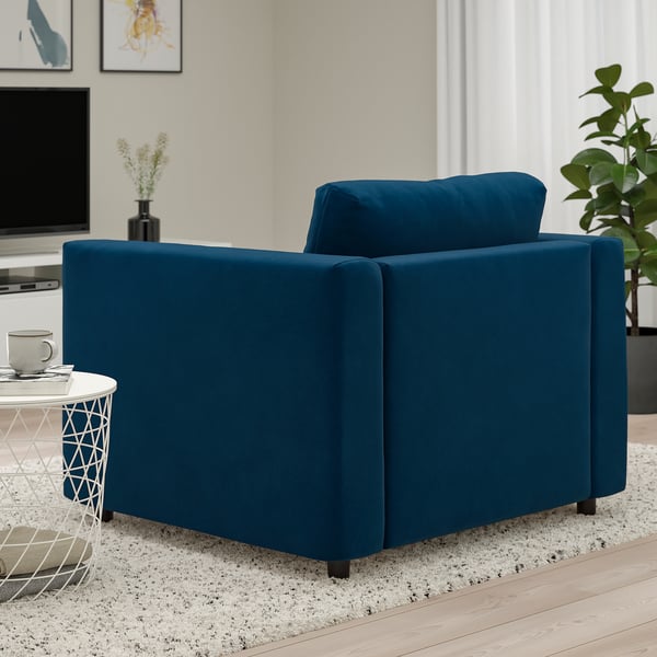 Una acogedora silla rinconera de terciopelo azul de la serie de sofás VIMLE, perfecta para una cómoda zona de estar.