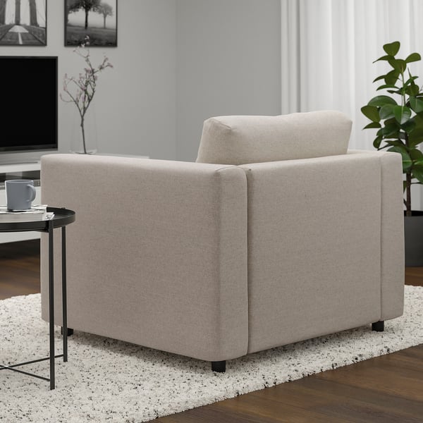 Sillón gris de la serie VIMLE sobre alfombra, mesa auxiliar con taza y decoración.
