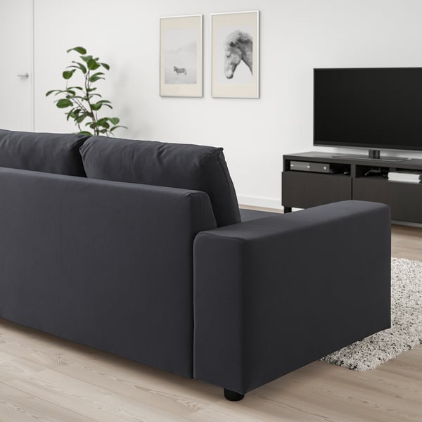 Sofá VIMLE negro sobre suelos de madera, mueble de tv, decoración minimalista.