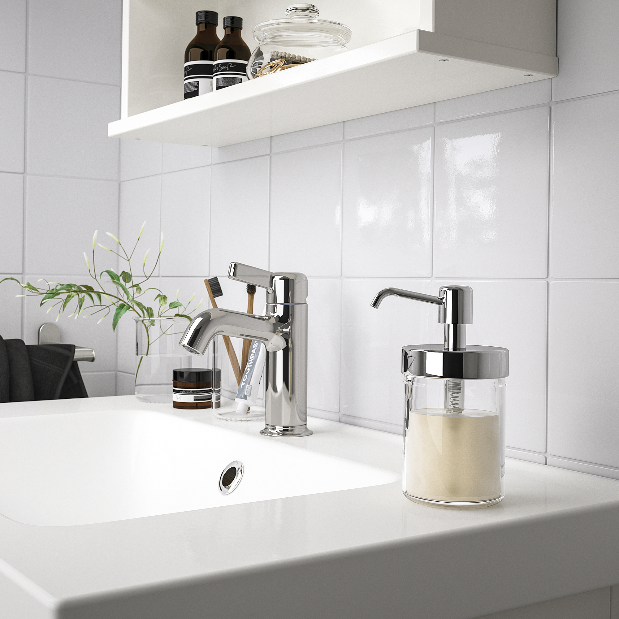 Un elegante dispensador de jabón VOXNAN con una taza de vidrio transparente y detalles cromados se encuentra sobre una encimera blanca en un elegante baño.
