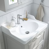 Lavabo de baño blanco con accesorios cromados, grifo VOXNAN, dispensador de jabón, soporte para cepillos de dientes.