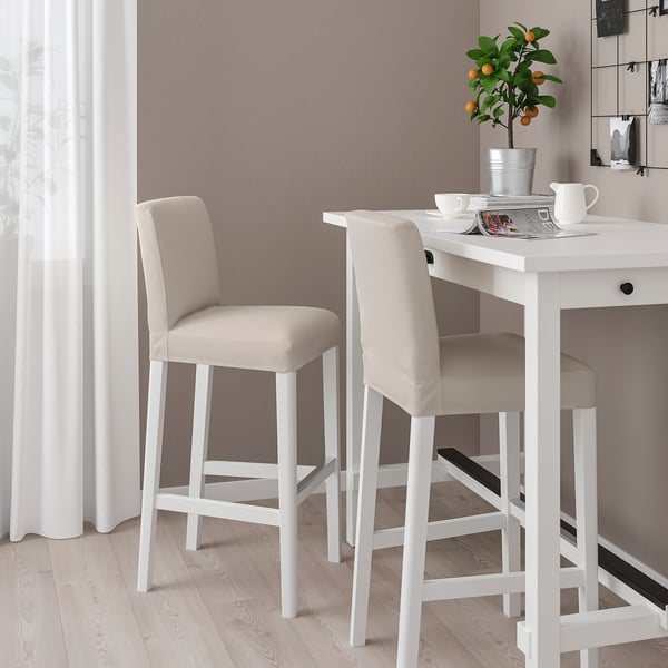 Jangela modernoa BERGMUND taburete zuriekin. Cojin beige, diseinu dotorea. Helduen tamaina, gortinen eta mahaiaren artean.