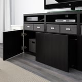 Tv BESTÅ beltzeko altzariak, apal estugarriekin eta biltegiratzearekin. Ate ireki bat, kaxa zuria barruan.