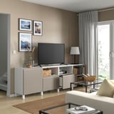 Egongelan, BESTÅ telebista-banku zuria. Telebista, dekorazioa, liburuak. Leiho handia gortinekin. Sofa beigea egurrezko mahaitxoaren ondoan.