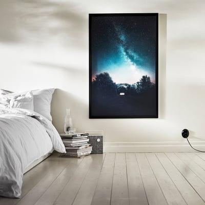 Ohe baten gainean marko beltza duten galaxia-irudi handi bat, logela-giro dramatiko eta abegitsua sortuz, dekorazio minimalistarekin.