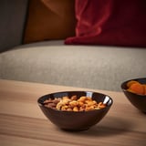 Fruitu lehorrez betetako katilu iluna, egurrezko mahai baten gainean, aperitiboak zerbitzatzeko egokia.